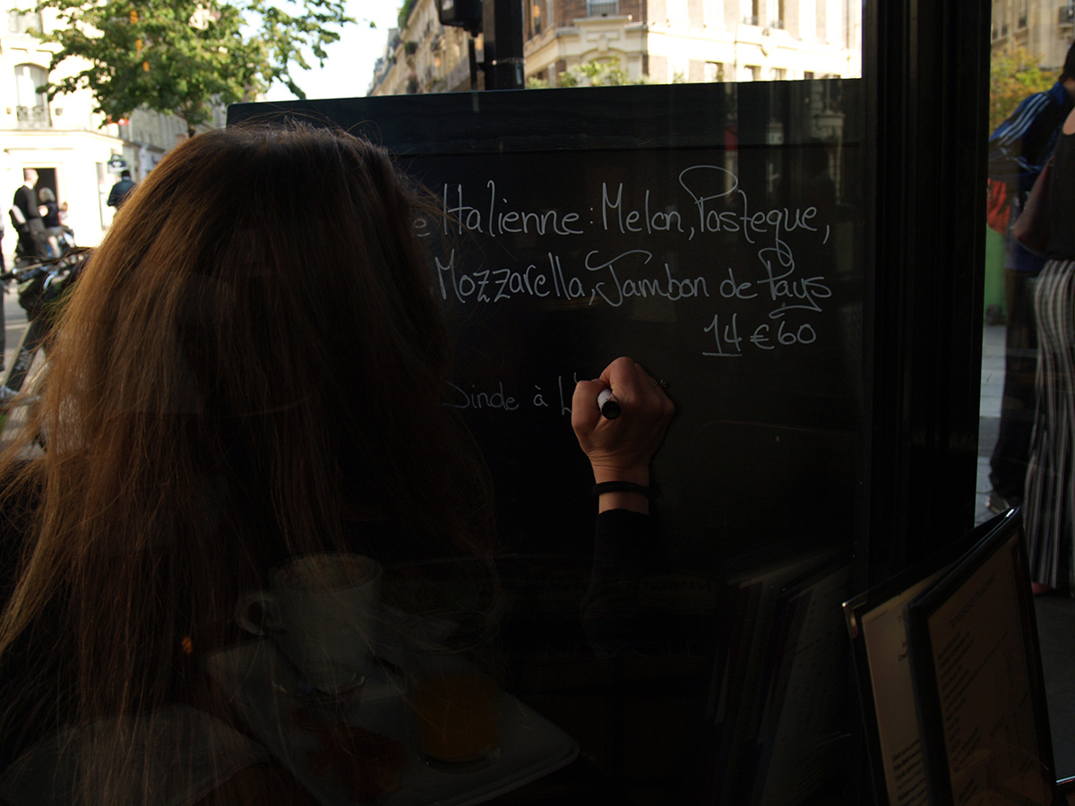 パリの文化・社会・歴史：黒板にメニューを書くカフェの店員